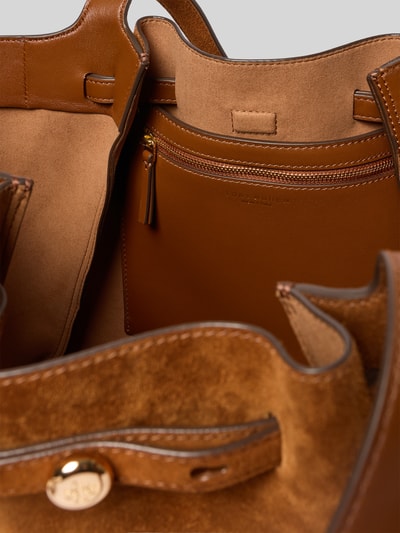 Produktfoto, Tote Bag in Suede-Optik von Tory Burch in warmem Braun mit Magnetverschluss, Reißverschlussfach, Logo-Detail, Hauptfach, Innenmaterial samtartige Textur, Maße: Breite 40 cm, Länge 2 cm, Tiefe 17 cm.