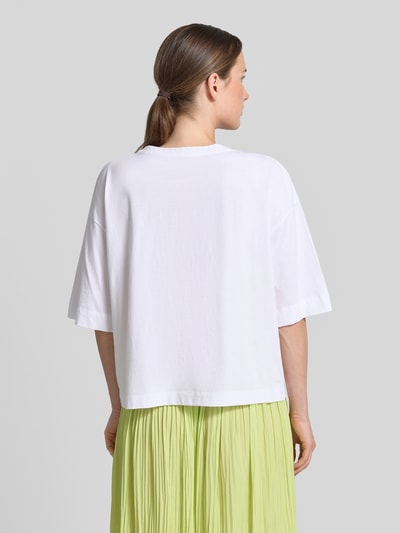 Modelka damska ma na sobie T-Shirt mit Motiv-Stitchings od Marc Cain, biała bawełna, luźny krój, widok całej sylwetki z tyłu.