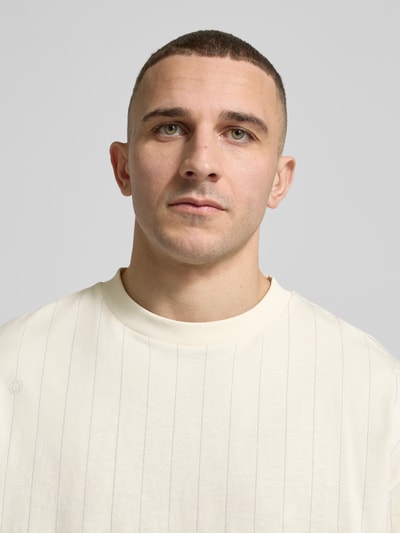 Männermodel trägt Regular Fit T-Shirt aus reiner Baumwolle Modell 'NORAYATI' von Hugo Blue mit Streifenmuster und Label-Smiley-Print, Optik:Allover-Muster, Rundhals, Kurzarm, Materialverarbeitung: Jersey, Nahaufnahme Oberkörper.