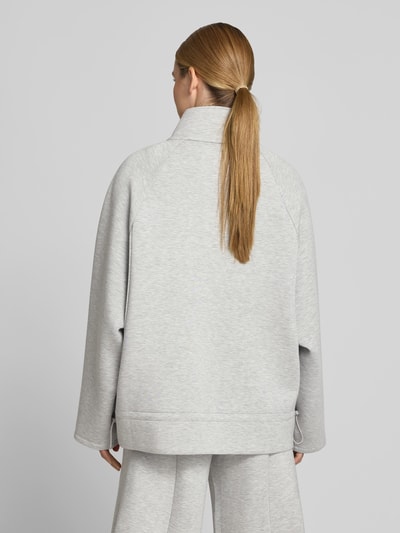 Frauenmodel trägt Sweatshirt aus Viskose-Mix von ROTATE in Hellgrau mit Stehkragen, taillierte Passform, Logo-Patch, Rückenlänge 69 cm, Ganzkörperansicht Rückansicht.
