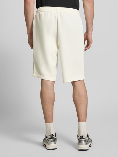 Mężczyzna nosi Shorts mit elastischem Bund od EA7 Emporio Armani, materiał z domieszką wiskozy, krój regular fit, kolor jasny, widok całej sylwetki od tyłu, szerokość w rozmiarze M: 41 cm, długość wewnętrzna nogawki w rozmiarze M: 28 cm.
