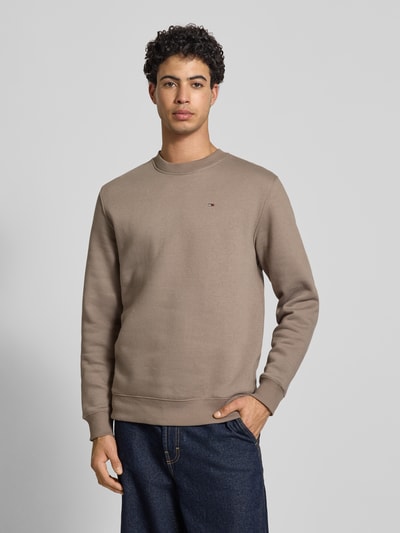 Mężczyzna model nosi Regular Fit Sweatshirt aus Baumwoll-Mix von Tommy Jeans, efekt: jednolity kolor, krój regular fit, wyhaftowane logo, okrągły dekolt, długi rękaw, zakończenia rękawów i dołu prążkowane, dzianina dresowa, mieszanka bawełny, Ganzkörperansicht von vorne.