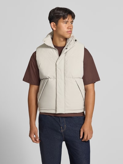 Mannelijk model draagt lichte bodywarmer met opstaande kraag, regular fit, verborgen ritssluiting, Model 'SOHO BODYWARMER' van JACK & JONES, ruglengte maat M 65 cm, schouderbreedte 43 cm, borstwijdte 59 cm, voorkant volledig zichtbaar, Ganzkörperansicht von vorne.