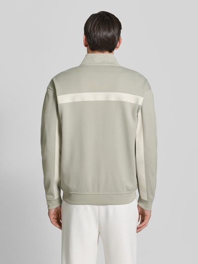 Männermodel trägt Relaxed Fit Sweatjacke mit Baumwoll-Anteil Modell 'DARTI' von HUGO, jednolity kolor, długi rękaw, chevron-tape, widok całej sylwetki z tyłu.