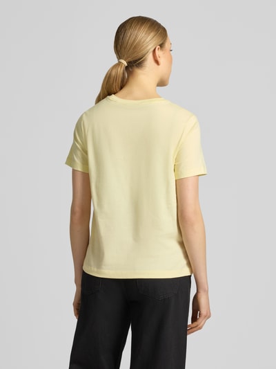 Modelka nosi T-Shirt mit Label-Print und Rundhalsausschnitt od Gant z bawełny, krój regular fit, okrągły dekolt, długość tyłu w rozmiarze S: 57 cm, jasny kolor, gładka tekstura, widok całej sylwetki z tyłu.