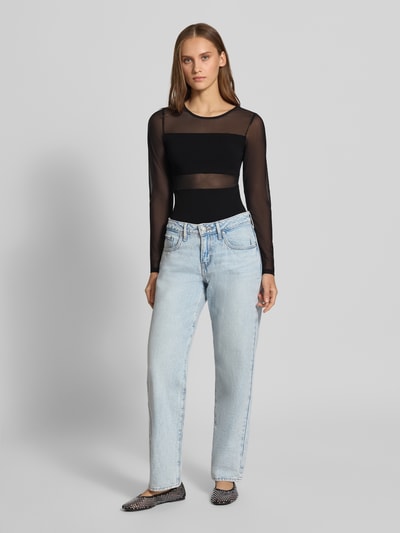 Modelka nosi Slim Fit Body w półprzezroczystej optyce model 'ESTHER' od ONLY, czarny materiał, jasne jeansy, widok całej sylwetki z przodu.