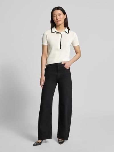 Frauenmodel trägt Regular Fit Strick-Shirt aus reiner Baumwolle Modell 'SLYSA' von HUGO, unifarben, kurzarm, mit Strukturmuster, Kontraststreifen und Logo-Stitching, kombinierbar mit weiter Hose; Ganzkörperansicht von vorne.