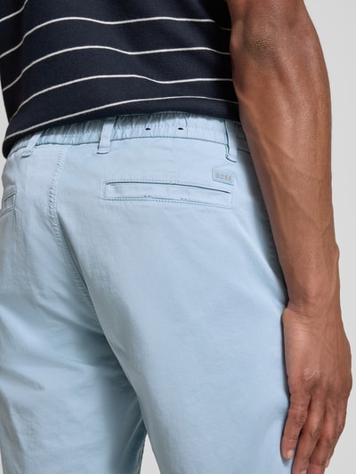 Männermodel trägt Tapered Chinoshorts aus Baumwoll-Mix von BOSS Orange in Hellblau mit Label Patch und Gürtelschlaufen, Nahaufnahme Rückansicht.