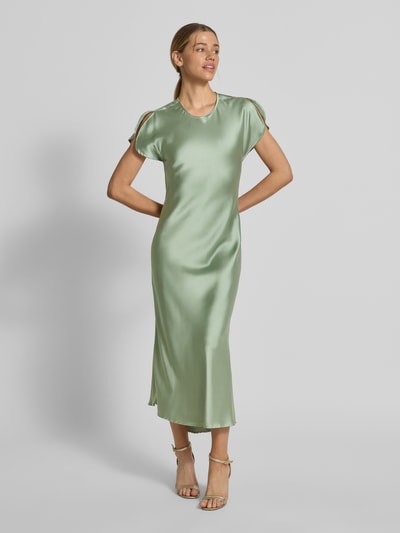 Frauenmodel trägt Cocktailkleid mit Rundhalsausschnitt Modell 'Miley' von GUIDO MARIA KRETSCHMER WOMAN aus grünem Satin, körpernaher Schnitt, Midi-Länge, Ärmelschlitz, Rückseitiger Schlüsselloch-Ausschnitt, Ganzkörperansicht von vorne.