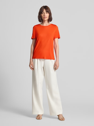 Frauenmodel trägt T-Shirt mit Rundhalsausschnitt von Fynch-Hatton in Orange, Relaxed Fit, 1/2-Arm, kombiniert mit weißer Hose, Ganzkörperansicht von vorne. Rückenlänge bei Größe S: 62 cm.