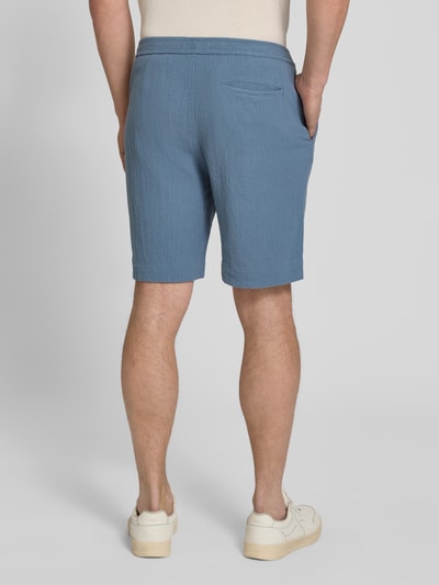 Männermodel trägt Regular Fit Shorts aus reiner Baumwolle Modell 'REGCAL' von SELECTED HOMME in Blau, unifarben, Ganzkörperansicht Rückansicht.