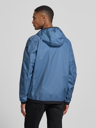 Männermodel trägt Jacke mit Kapuze Modell 'KOS' von Killtec in blau, gerader fit, elastische mouwuiteinden, labelpatch, Ganzkörperansicht Rückansicht.