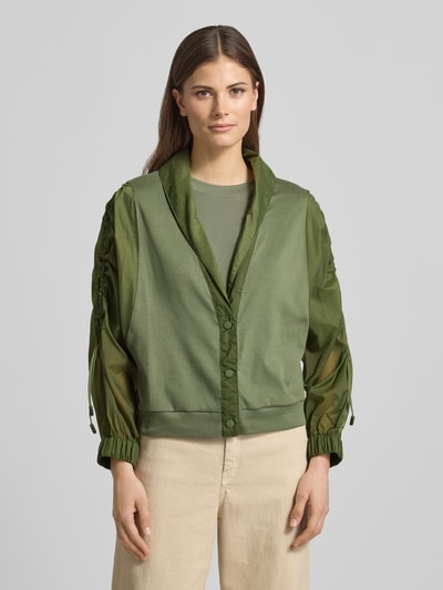 Kobiece modelka nosi Relaxed Fit Leichte Jacke im Material-Mix od Marc Cain, efekt: jednolity kolor, krój relaxed fit, szalowy kołnierz, marszczenie, zapięcie na listwę guzikową, rękaw o dł. 3/4, wykończenie materiału: satyna, szyfon, materiał: mieszanka bawełny, zielona, beżowe spodnie, Ganzkörperansicht von vorne.