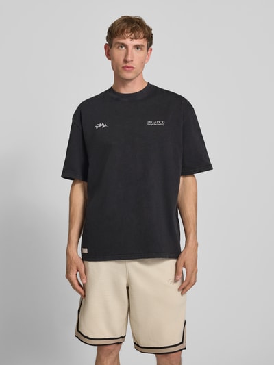 Männermodel trägt Oversized Herren T-Shirt aus reiner Baumwolle, Label-Print, Rundhalsausschnitt, Modell 'Trofa' von PEGADOR, Ganzkörperansicht von vorne.