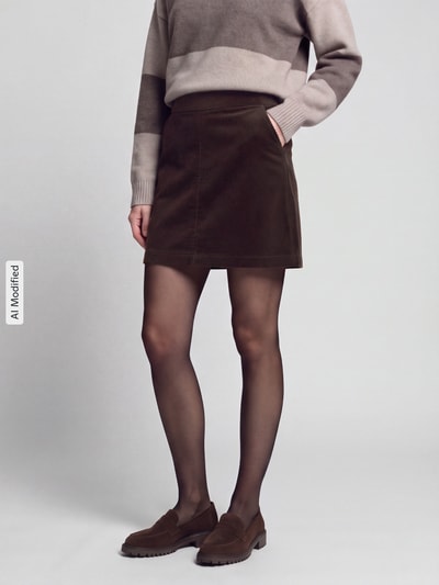Frauenmodel trägt A-Linie Mini-Rock aus Baumwoll-Mix von Marc O'Polo DENIM, dunkles Braun, glatte Textur, Ganzkörperansicht von vorne, KI-modifiziertes Bild.