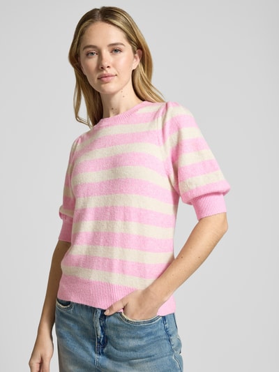 Frauenmodel trägt Regular Fit Strickpullover mit Crew Neck Modell 'DOFFY' von Vero Moda, Optik: Unifarben, Strickoptik, Label-Stitching-Applikation, Rundhals, 1/2-Arm, Ärmelabschluss gerippt, Rumpfabschluss gerippt, Materialverarbeitung: Strick, Querstreifen in Rosa und Creme. Ganzkörperansicht von vorne.