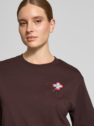 Vrouwenmodel draagt oversized fit t-shirt uit puur katoen met geborduurd logo en bloemenborduursel van closed, halflange mouwen, detailopname bovenlichaam