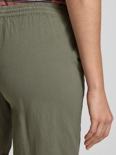 Frauenmodel trägt Shorts mit elastischem Bund Modell 'Cissie' von Soyaconcept aus Reine Baumwolle in Olivgrün, Detailaufnahme Rückansicht. Regular-Fit, Bundweite bei Größe S: 38 cm, Innenbeinlänge bei Größe S: 20 cm, strukturierte Textur.