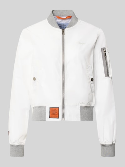 Produktfoto, weiße Bomberjacke mit Label-Patch und Reißverschlusstasche am Ärmel von Original Bombers, graue Bündchen, glatte Textur.