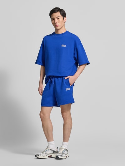 Männermodel trägt Shorts mit Logo Modell 'PLIZZY' von American Vintage aus Reine Baumwolle im Relaxed-Fit mit Tunnelzug, Ganzkörperansicht von vorne.