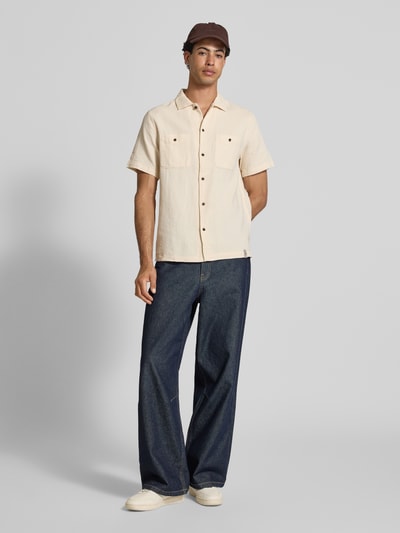 Männermodel trägt Regular Fit Freizeithemd mit Kentkragen und Brusttaschen von Superdry aus reiner Baumwolle, Strukturmuster, beige, Ganzkörperansicht von vorne.