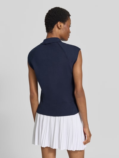 Frauenmodel trägt Relaxed Fit Weste aus Baumwoll-Mix von Tommy Hilfiger in Dunkelblau zu weißem Faltenrock, Ganzkörperansicht Rückansicht, Damen Weste von Tommy Hilfiger.