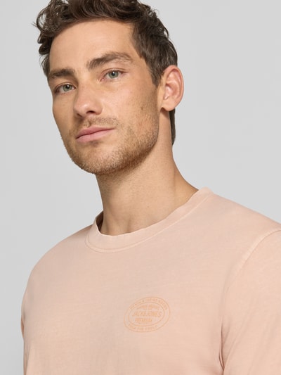 Männermodel trägt T-Shirt mit Label-Print Modell 'FELIX' von Jack & Jones Premium aus Reine Baumwolle, Regular-Fit, Rundhalsausschnitt, Nahaufnahme Oberkörper.