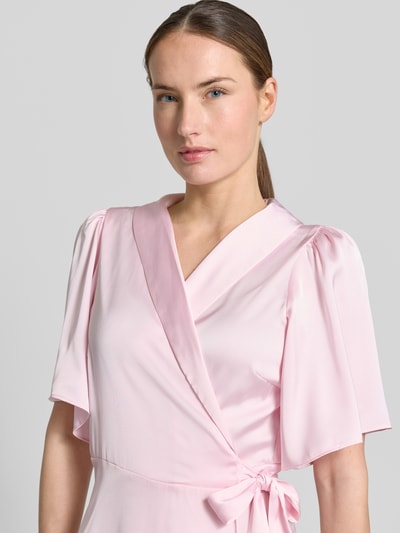 Frauenmodel trägt Midikleid in Wickel-Optik Modell 'VIENNA RAVENNA' von Vila aus rosa Satin, taillierter Schnitt, V-Ausschnitt, Nahaufnahme Oberkörper. Rückenlänge bei Größe 36: 125 cm, Brustweite bei Größe 36: 50 cm, Ärmellänge bei Größe 36: 30 cm.