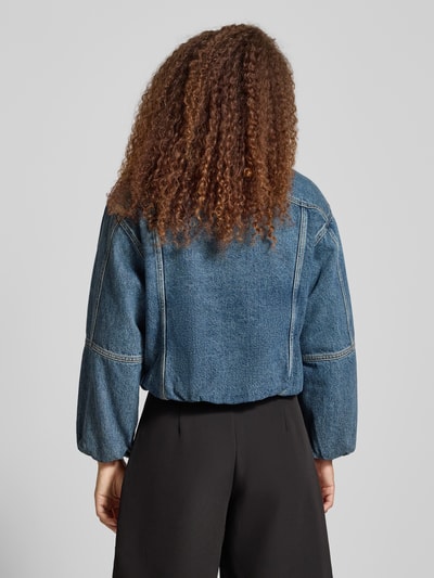 Frauenmodel trägt Cropped Jeansjacke mit Knopfleiste von Calvin Klein Jeans in mittlerem Blau, Reine Baumwolle, Lockerer-Schnitt, Ganzkörperansicht Rückansicht.