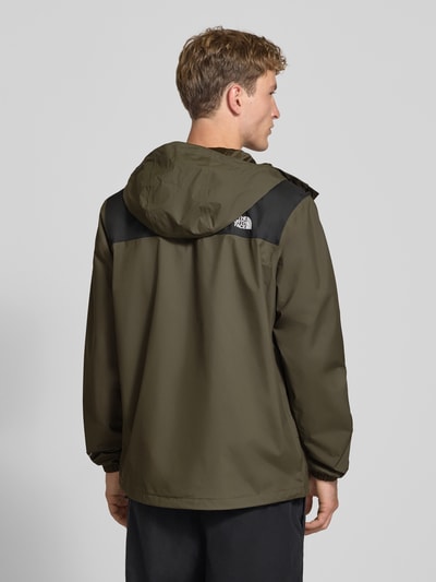 Männermodel trägt Jacke mit Label-Print Modell 'ANTORA' von The North Face in Olivgrün mit schwarzen Schulterpartien, Ganzkörperansicht Rückansicht. Kontext: Gerade Passform, Kapuze mit Tunnelzug, Label-Print, Reißverschlusstaschen, durchgehender Reißverschluss mit Abdeckleiste, elastische Ärmelabschlüsse, Rückenlänge bei Größe M 74 cm, Schulterbreite 47 cm, Brustweite 58 cm, Ärmellänge 68 cm.