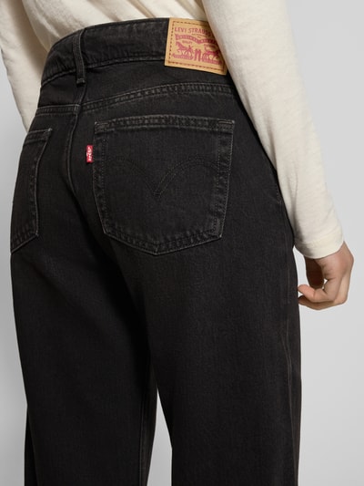 Frauenmodel trägt Superlow Loose Fit Jeans mit Eingrifftaschen von Levi's®, reine Baumwolle, schwarze Denimstruktur, Detailaufnahme Rückansicht.