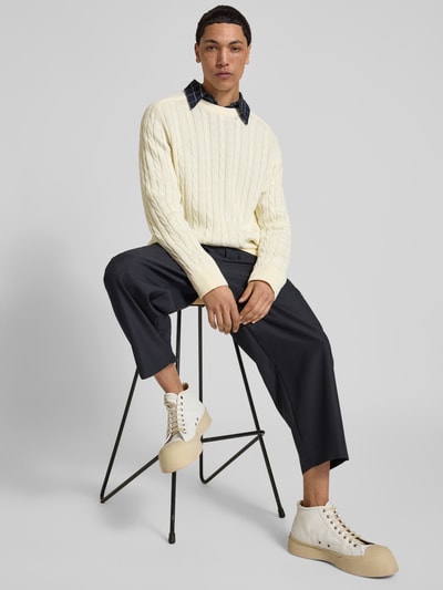 Männermodel trägt Slim Fit Pullover in Strick-Optik von Filippa K in Creme mit Rundhalsausschnitt, reine Baumwolle, Ganzkörperansicht von vorne.