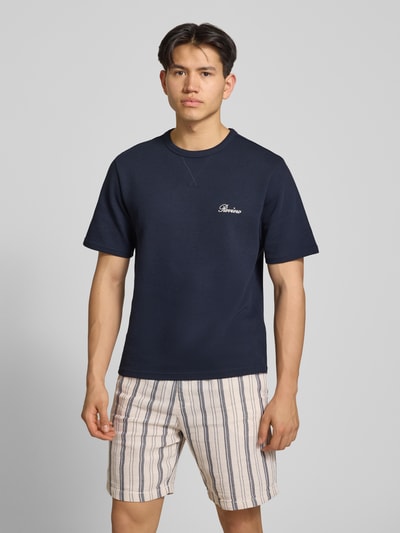 Männermodel trägt T-Shirt mit Label-Stitching von REVIEW in Dunkelblau, Waffelstruktur, gerader Schnitt, Ganzkörperansicht von vorne.