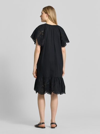 Modelka nosi sukienka mini Relaxed Fit Minikleid mit floraler Lochstickerei von Christian Berg Woman Selection, czarna bawełna, haft angielski, dekolt z lamówką, krótki rękaw, długość tyłu w rozmiarze 36: 74 cm, szerokość w rozmiarze 36: 34 cm, długość rękawów w rozmiarze 36: 26 cm, widok całej sylwetki z tyłu.