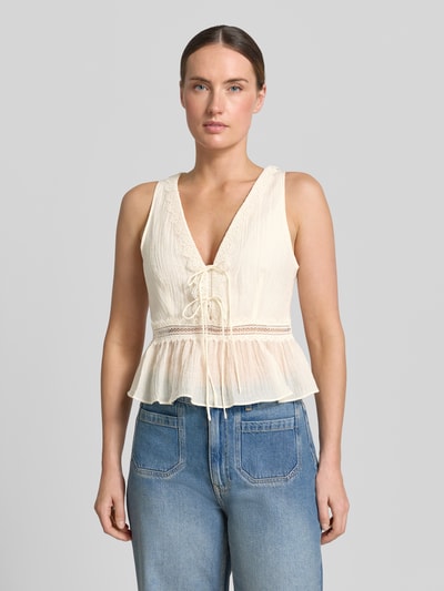 Frauenmodel trägt Top aus Lyocell-Mix mit Zierschleifen Modell 'Elena' von Mango, cremefarben, V-Ausschnitt, Loch-Stitching, tailliert, ärmellos, Ganzkörperansicht von vorne