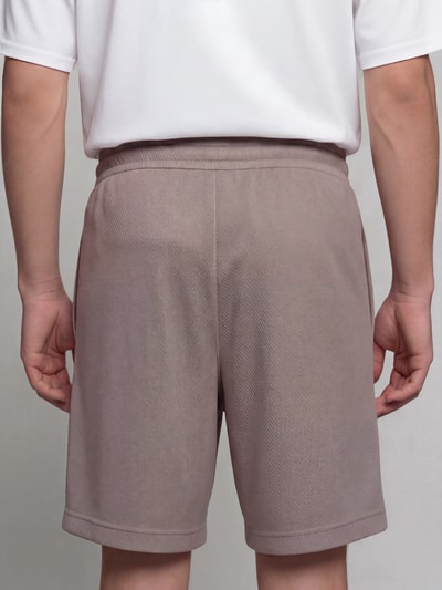 Männermodel trägt Relaxed Fit Sweatshorts aus Baumwoll-Mix 'ESS ELEVATED' von PUMA, beige, glatte Textur, Ganzkörperansicht Rückansicht, Herren Sweatshorts von PUMA Performance.
