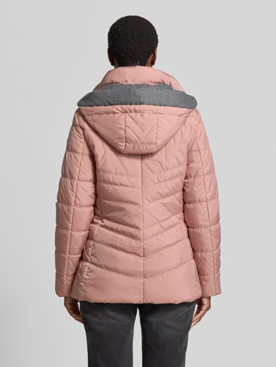 Männermodel trägt 'Jacke in Stepp-Optik mit Kapuze' von FUCHS SCHMITT w kolorze jasnoróżowym, z efektem pikowania, kaptur, taliowany krój, podszewka, wpuszczane kieszenie z zamkiem błyskawicznym, długość tyłu w rozmiarze 36: 74 cm, szerokość ramion w rozmiarze 36: 40 cm, szerokość klatki piersiowej w rozmiarze 36: 48 cm, długość rękawów w rozmiarze 36: 64 cm, widok całej sylwetki z tyłu.