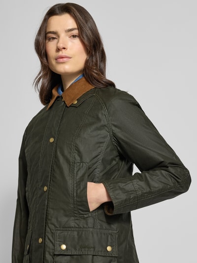 Frauenmodel trägt Wachsjacke aus reiner Baumwolle von Barbour in Olivgrün mit Umlegekragen, Pattentaschen, Regular-Fit, Nahaufnahme Oberkörper.