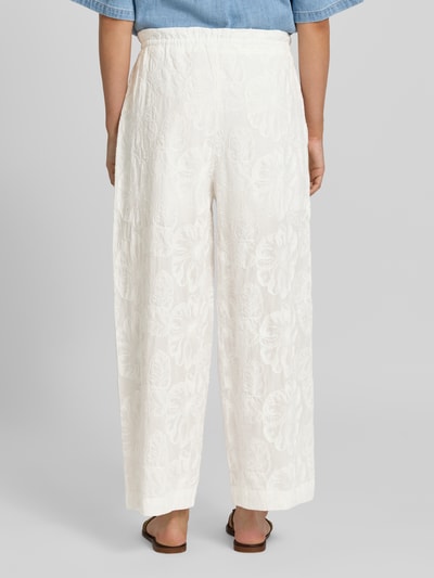 Frauenmodel trägt Wide Fit Stoffhose mit floralem Allover-Design von Mango aus Reine Baumwolle, Weiß mit strukturierter Textur, Ganzkörperansicht Rückansicht.