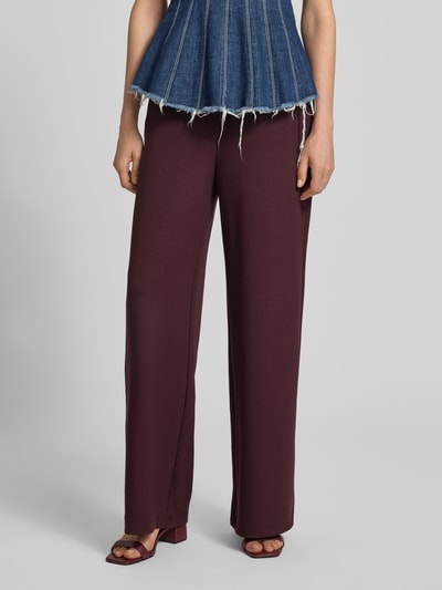 Frauenmodel trägt Relaxed Fit Sweathose aus Viskose-Mix Modell 'Style.Maine' von Brax in Dunkelrot, fließender Stoff, Damen Sweathose, Nahaufnahme Unterkörper.