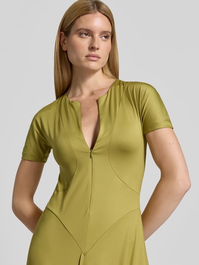 Frauenmodel trägt Midikleid mit verlängerter Rückseite von Victoria Beckham in Olivgrün, elastischer Material-Mix, Nahaufnahme Oberkörper.