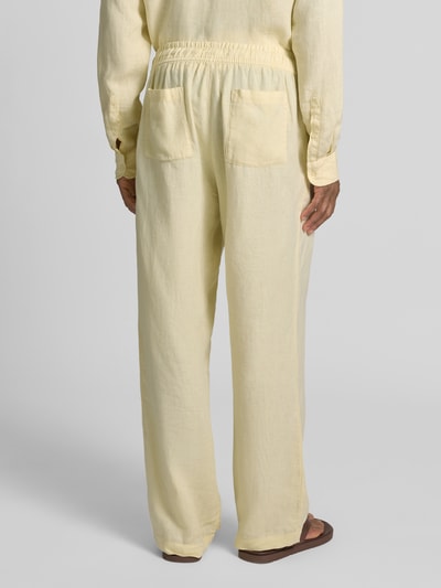 Männermodel trägt Leinenhose mit elastischem Bund von MCNEAL in Hellgelb, Regular-Fit, reine Leinen, Tunnelzug, Rückansicht Ganzkörperansicht.