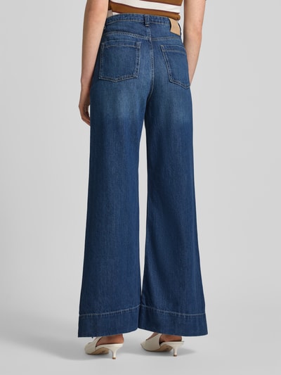 Frauenmodel trägt Flared Jeans aus Baumwoll-Mix Modell 'C_MARLENE' von BOSS im Denim-Look mit Label-Patch, Nieten, Gesäßtaschen, Longline Länge, Ganzkörperansicht Rückansicht.