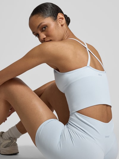 Frauenmodel trägt Crop Top mit überkreuzten Trägern von aim'n in Hellblau, Material-Mix mit Stretch, Rückenlänge 40 cm, Ganzkörperansicht Rückansicht.