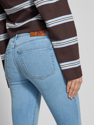 Frauenmodel trägt Slim Fit Jeans mit Logo-Patch von Calvin Klein Jeans im hellblauen 5-Pocket-Design aus elastischem Baumwoll-Mix, Detailaufnahme Rückansicht.