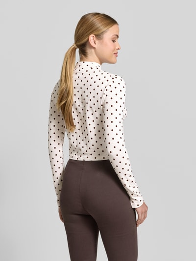 Frauenmodel trägt Cropped Longsleeve mit Polka Dots - curated by Mary Braun von Style Icon Collection, Stehkragen, Regular-Fit, Körpernahe Passform, Langärmelig, Rückenlänge bei Größe S 42 cm, Braun und Weiß, Ganzkörperansicht Rückansicht.