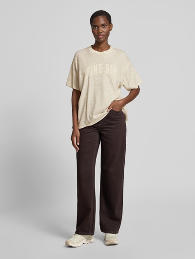 Frauenmodel trägt Oversized T-Shirt mit Logo-Print von Anine Bing in Beige mit Allover-Animal-Print aus reiner Baumwolle, Rundhalsausschnitt, Oversized-Fit, Rückenlänge bei Größe S 64 cm, Ganzkörperansicht von vorne.