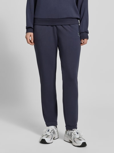 Frauenmodel trägt Sweatpants mit elastischem Bund und Logo von LIU JO SPORT im Modal-Mix mit Stretch-Anteil, Regular-Fit, Logo-Detail, dunkelblau, glatte Textur, Innenbeinlänge bei Größe S 72 cm, Nahaufnahme Unterkörper von vorne.