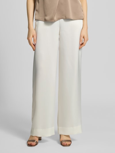 Frauenmodel trägt Slim Fit Weite Hose mit Schiebehaken und verdecktem Reißverschluss Modell 'HASELI-1' von HUGO, Optik: Unifarben, Passform: Slim-Fit, High-Waist, Materialverarbeitung: Satin, cremefarbene, glatte Textur, Nahaufnahme Oberkörper.