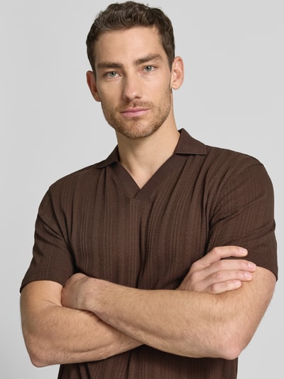 Männermodel trägt Regular Fit Poloshirt aus Baumwoll-Mix Modell 'TRAVIS' von SELECTED HOMME in Braun, Struktur, Optik: Unifarben, Nahaufnahme Oberkörper.